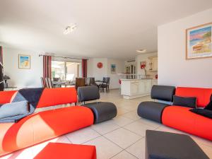 una gran sala de estar con muebles de color rojo y naranja. en Villa Les Villas de l'Etang by Interhome, en Canet-en-Roussillon