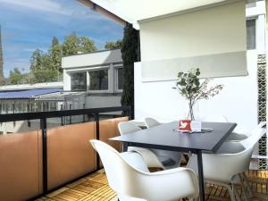 balcón con mesa negra y sillas blancas en Apartment Lago di Lugano-5 by Interhome, en Bissone