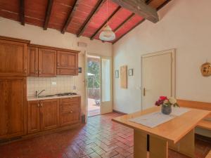 a kitchen with wooden cabinets and a table with a vase of flowers at Apartment Fattoria Petraglia - Terrazza by Interhome in Monteriggioni