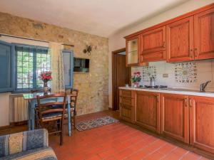 a kitchen with wooden cabinets and a table in a room at Apartment Fattoria Petraglia - Cedro by Interhome in Monteriggioni