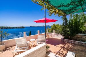a patio with a table and chairs and a red umbrella at Apartments Lovro in Dubrovnik
