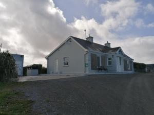 una casa blanca con un banco delante en Atlantic Way Farmhouse, en Lahinch
