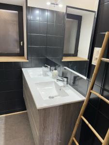 een badkamer met een witte wastafel en een spiegel bij Gite du vieux Morat in Saint-Bonnet-Tronçais