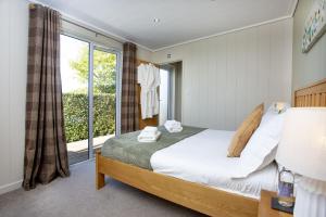 a bedroom with a bed and a large window at Whileaway Lodge, Strawberryfield Park in Cheddar