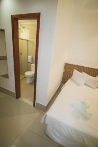 a bedroom with a bed and a bathroom with a toilet at Ramada by Wyndham Porto Seguro Praia in Porto Seguro