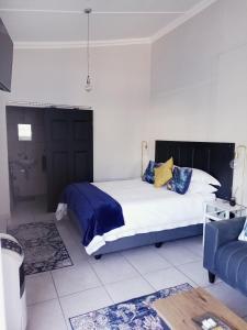 a bedroom with a bed with blue and yellow pillows at Dalau on Main in Paarl