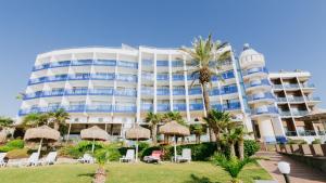 a hotel with chairs and palm trees and a building at Faustina Hotel & Spa in Güzelçamlı