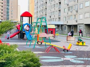 um parque infantil com equipamento de brincar colorido numa cidade em Тихая гавань em Almaty