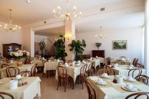 a restaurant with white tables and chairs and a chandelier at Hotel de la Ville in Senigallia