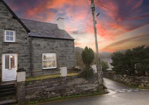a stone house on a street with a sunset at Uwch Ogwen in Bethesda