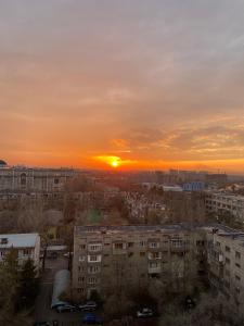 een zonsondergang boven een stad met hoge gebouwen bij ЖК Весна in Alma-Ata