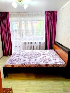 una camera da letto con un letto con tende rosse e una finestra di 4-х комнатная квартира Центр ЦУМ a Qostanay