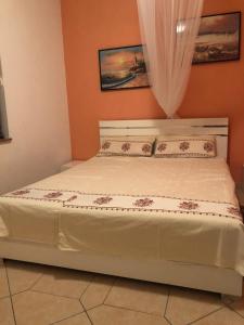 ein Schlafzimmer mit einem Bett mit weißer Bettwäsche und einem Vorhang in der Unterkunft Haus mit Garten Rtina Miocic in Rtina