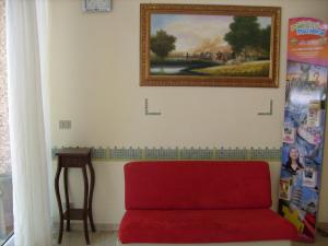 a living room with a red couch and a painting on the wall at Hotel Tiziana in Rimini