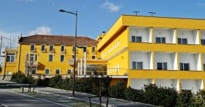 CarvalhalPalace Hotel Astúrias & Spa的街道旁的一座黄色和白色的建筑