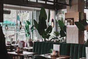 un restaurante con un banco verde, mesas y plantas en Hotel de la Bourse en Maastricht