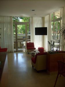 a living room with a couch and chairs and a tv at Hotel Tiziana in Rimini