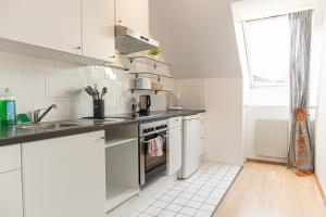 een keuken met witte kasten, een wastafel en een fornuis bij Vibrant Aparment perfect for Long Stays in Wenen