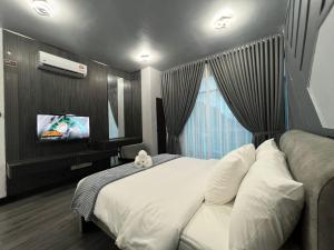 a bedroom with a large bed and a tv at SAMSARA Studio Apartment with Pool in Gua Musang