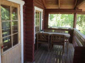 un porche de una cabaña con mesa y sillas en Päivänsäde Cottage en Toivakka