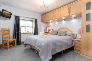a bedroom with a large bed and a chair at Y Beudy, Converted Former Dairy in Conwy