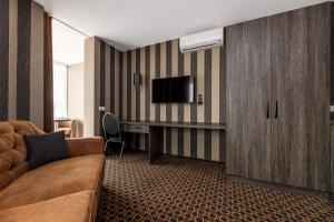 a hotel room with a couch and a flat screen tv at Resort Hotel Elija in Šventoji