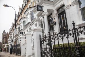 una casa blanca con una valla de hierro forjado en The W14 Kensington, en Londres