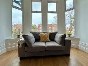 a couch sitting in a living room with windows at Lathom Road Central in Southport