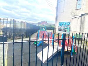 un parque infantil con un tobogán frente a una valla en Merseyside en Birkenhead