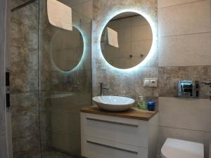 a bathroom with a sink and a shower with two mirrors at Apartament Plac Piastowski 1 in Jelenia Góra