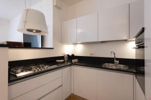 a white kitchen with a stove and a sink at BnButler - Verona 12, Porta Romana District in Milan
