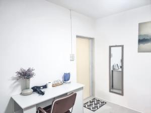 a white bathroom with a chair and a mirror at The zai Apartment in Ban Krathum Lom
