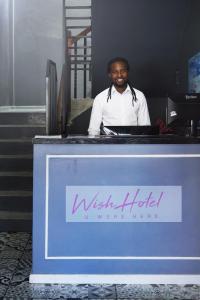 een man achter een bureau met een bord bij Wish U Were Here in Kaapstad