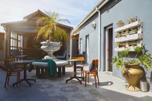 een patio met een tafel en stoelen en een vaas bij Wish U Were Here in Kaapstad
