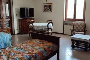 1 dormitorio con 1 cama, TV y sillas en Il canto del gallo - Country house, en Cassinasco