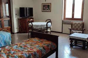 a bedroom with a bed and a tv and chairs at Il canto del gallo casa vacanza in Cassinasco