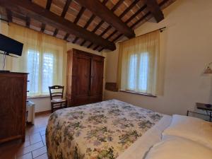 a bedroom with a bed and a tv and windows at Agriturismo e Cantina La Sabbiona in Faenza