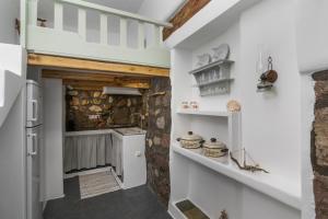 - une cuisine avec des murs blancs et un mur en pierre dans l'établissement Akrogialis Sirma Klima, à Adamas