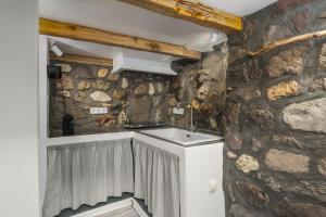 La salle de bains est pourvue d'un lavabo et d'un mur en pierre. dans l'établissement Akrogialis Sirma Klima, à Adamas