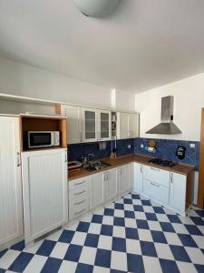 cocina con armarios blancos y suelo a cuadros en Apartmán Obchodná, en Staré Mesto