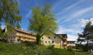 un grand bâtiment jaune sur une colline plantée d'arbres dans l'établissement Michlhof, à Zeil