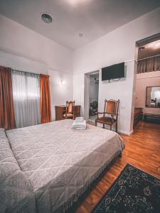 a bedroom with a bed and two chairs and a television at Hotel Americano in Buenos Aires