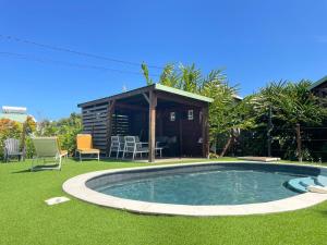 a small swimming pool in a yard with a shed at Au cœur du papillon piscine collective en famille in Goyave