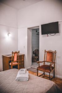a bedroom with a bed and two chairs and a desk at Hotel Americano in Buenos Aires