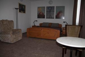 uma sala de estar com uma cama, uma mesa e uma cadeira em Három Tarka Macska Apartmanok em Sárospatak