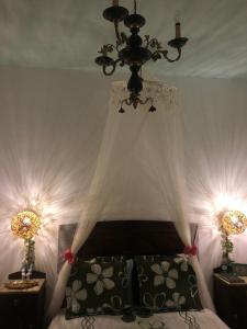 a bedroom with a bed with a chandelier and two night stands at Casal dos Carpinteiros - Carpenters Couple in Silveira