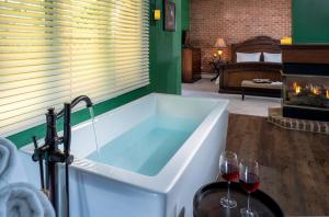 a bath tub in a room with two glasses of wine at The Yellow House on Plott Creek in Waynesville