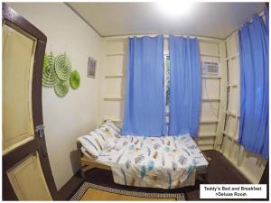 um pequeno quarto com uma cama e cortinas azuis em Teddys Bed & Breakfast lodge 