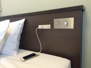 uma cama com um telemóvel ligado a uma parede em Shizutetsu Hotel Prezio Shizuoka-Ekikita em Shizuoka