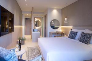 a bedroom with a large white bed and a living room at Cora Hotel & Spa in Afitos